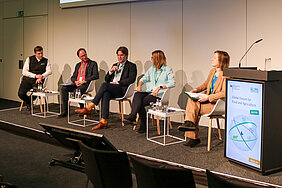 Four panellists and a moderator sit on the stage.